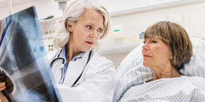Mature Female Doctor Checking X-Ray With Mature Patient
