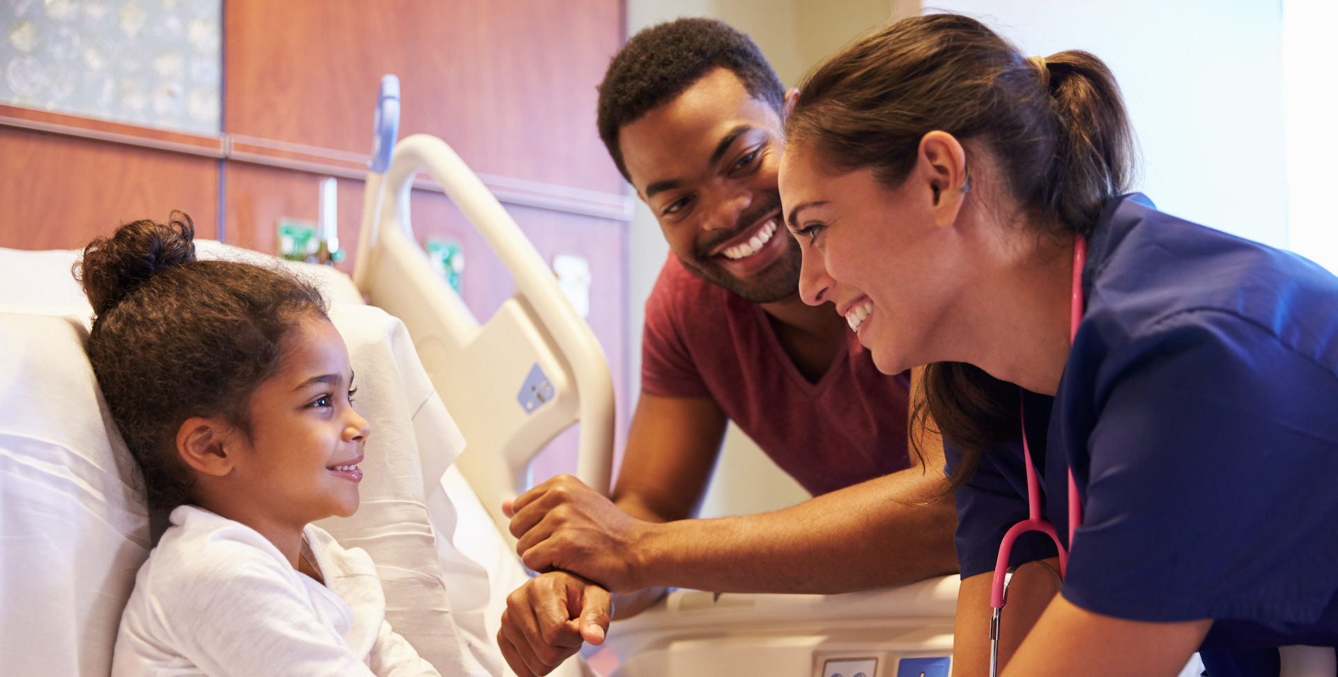 Pediatrician Visiting Father And Child In Hospital Bed