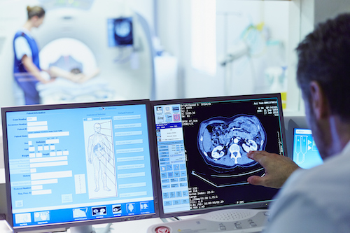 Male doctor running CAT scan from control room at hospital