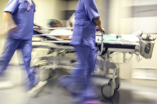 Doctors and nurses pulling hospital trolley through ER