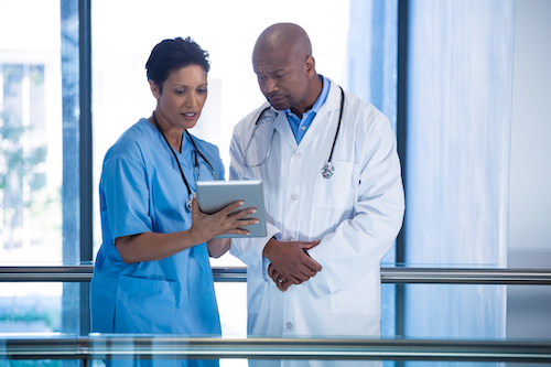 Male doctor and nurse using digital tablet in corridor