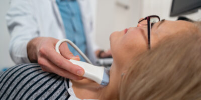 Endocrinologist doing ultrasound of thyroid gland on a senior female patient