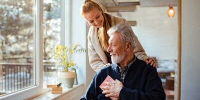 visionary-society Elderly man in wheelchair holding book and talking to daughter.