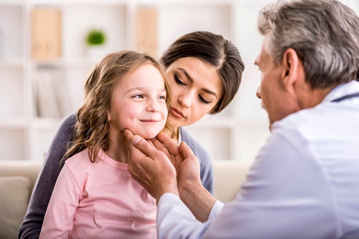 Doctor checking child who is sitting in her mother's lap.